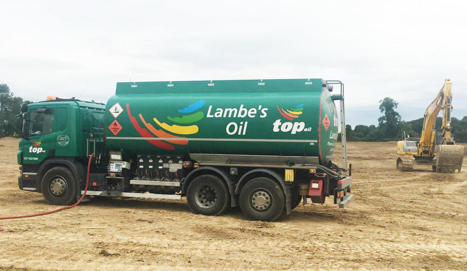 A Lambes Oil truck refueling a commercial machine on-site.